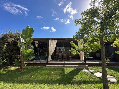 Vue du jardin de la Villa Maé avec terrasse pergola ombragée, transats et paysage tropical luxuriant aux Villas d'A Storia, Ghisonaccia