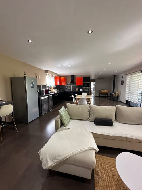 Spacieuse villa moderne avec séjour ouvert, canapé crème, cuisine noire aux touches rouges et salle à manger aux Villas d'A