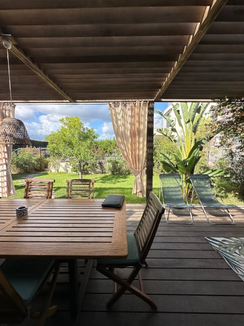 Terrasse couverte de la Villa Maé avec table à manger, transats et vue sur le jardin à Ghisonaccia