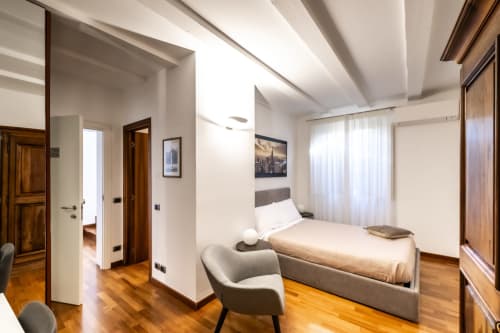 Camera Melograno Superior presso Corte Livia B&B a Forlì con letto matrimoniale, poltrona grigia, pavimenti in legno e finestre con vista sul giardino