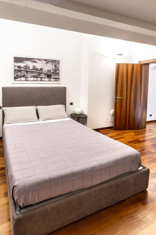 Camera Deluxe Betulla presso Corte Livia B&B a Forlì con letto matrimoniale, testiera grigia, pavimenti in legno e opere d'arte dello skyline cittadino