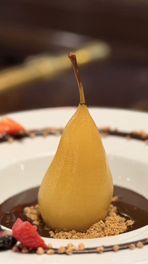 Poire pochée en dessert avec sauce chocolat et garniture croustillante à l'Hôtel Beau Rivage