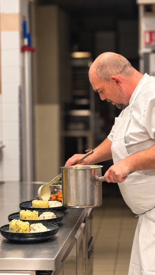 Chef en train de dresser un plat à la cuisine de l'Hôtel Beau Rivage à Chambéry, France