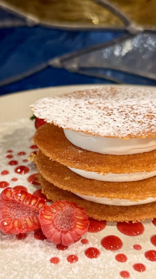 Gâteau éponge multicouche garni de crème et sucre glace, orné de framboises fraîches à l'Hôtel Beau Rivage