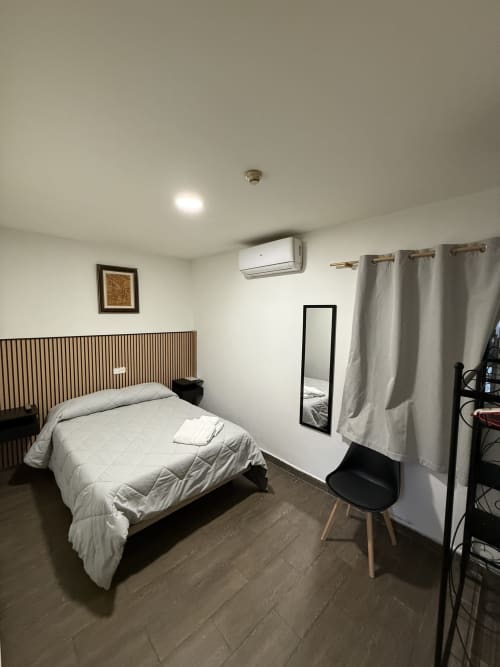 Moderna habitación doble en Hostal3hermanos de Getafe con cama queen, aire acondicionado, espejo y cortinas grisáceas
