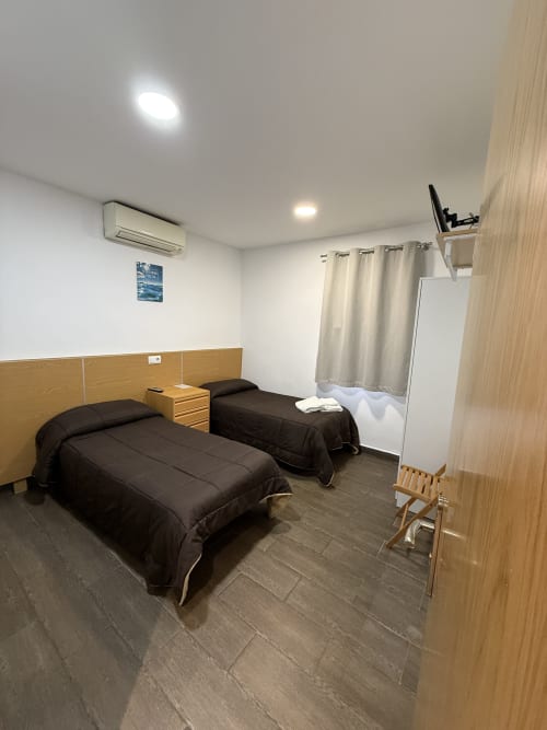 Habitación doble en Hostal3hermanos de Getafe con dos camas, cabeceros de madera, aire acondicionado y piso de baldosas