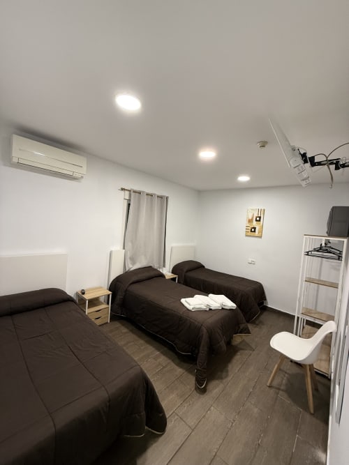 Habitación triple en Hostal3hermanos, Getafe con tres camas, aire acondicionado, iluminación moderna y diseño accesible a nivel del suelo