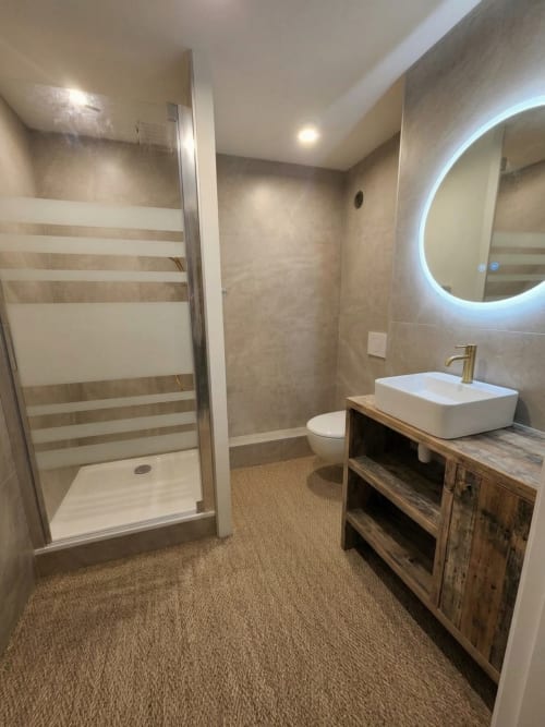 Salle de bain moderne du Chalet du Vallon 16, La Plagne : douche vitrée, vasque en bois, miroir éclairant, toilettes