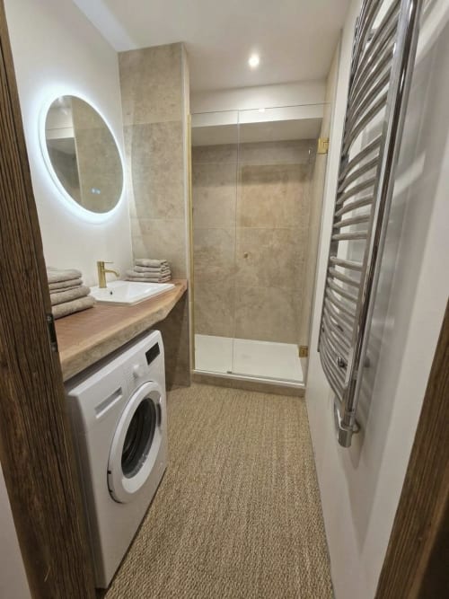 Salle de bain moderne au Chalet du Vallon 16, La Plagne avec douche, miroir lumineux, lavabo et sèche-serviettes électrique