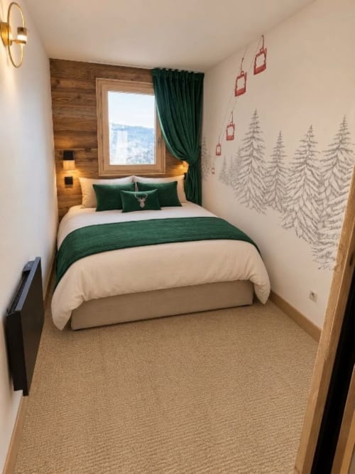Chambre alpine cosy aux Étoiles de la Plagne avec fresque forestière, accents verts, tête de lit en bois et vue montagne