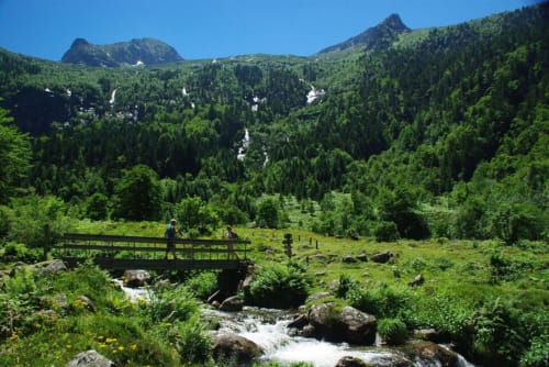 Vallée de montagne près de Seix avec pont en bois enjambant un ruisseau, forêts et sommets à la Maison Du Haut Salat
