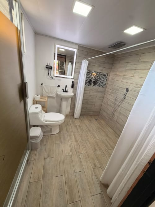 Baño moderno en villa Volcán Irazú de Chalets Vistas del Poás, Heredia, con piso en tonos madera y lavamanos pedestal
