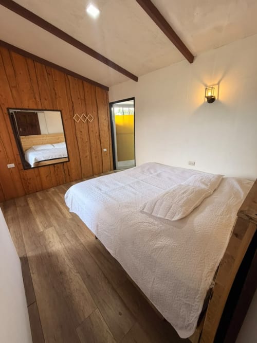 Dormitorio espacioso en Chalets Vistas del Poas con cama queen, armario de madera con espejo, vigas de madera vista y vistas a la montaña