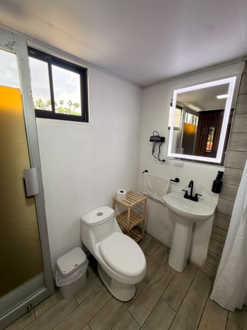 Baño moderno en villa Volcán Irazú de Chalets Vistas del Poás, Heredia con inodoro blanco, lavamanos de pedestal y espejo iluminado.