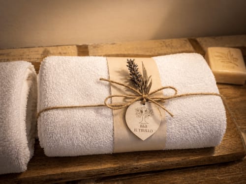 Asciugamani bianchi arrotolati legati con spago e grano secco in esposizione in legno presso Il Trullo B&B, Terlizzi Italia