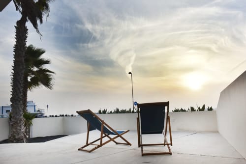 Terraza de Sunset House en El Cotillo con tumbonas, palmera y vistas al mar en la hora dorada