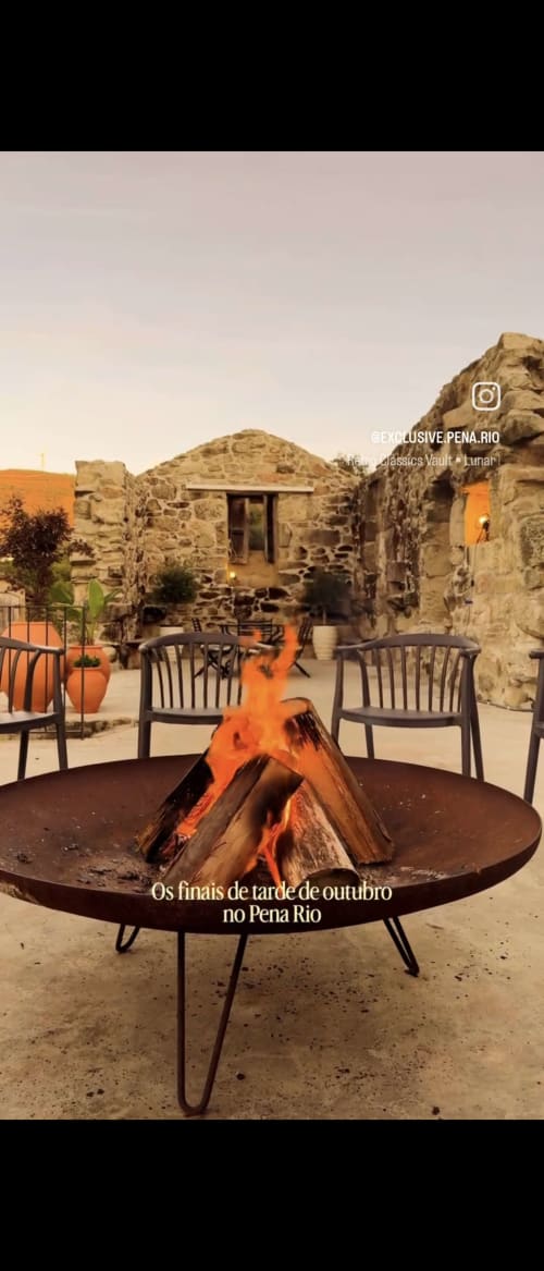 Fogueira com chamas no pátio do hotel Exclusive Pena Rio em Ribeira de Pena, Portugal, com edifícios de pedra e lounge