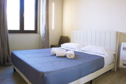 Chambre spacieuse au Sikania Agri Relais de Caccamo avec lit bleu, oreillers blancs, serviettes roulées, climatisation