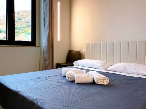 Chambre moderne de l'hôtel Sikania Agri Relais à Caccamo avec vue montagne, serviettes roulées et mobilier contemporain