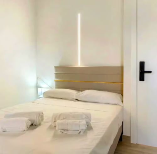 Chambre moderne au Sikania Agri Relais à Caccamo avec literie blanche, oreillers, néon et poignée de porte noire