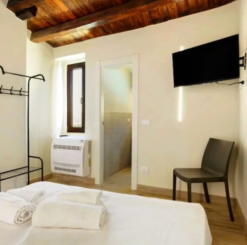 Chambre moderne au Sikania Agri Relais à Caccamo avec lit blanc, poutres apparentes, TV et vue sur les montagnes