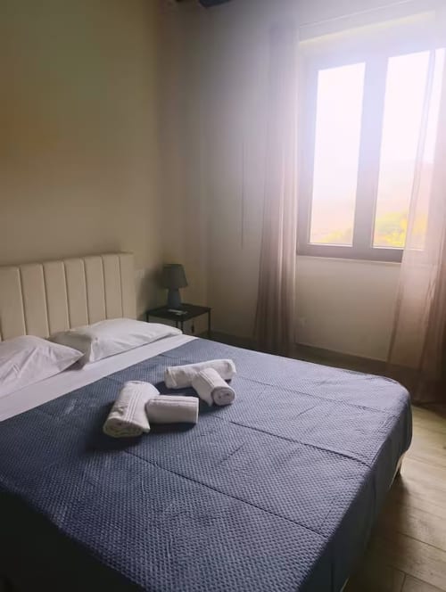 Chambre double standard Briogna au Sikania Agri Relais à Caccamo avec vue montagne, oreillers blancs et serviettes roulées sur le lit