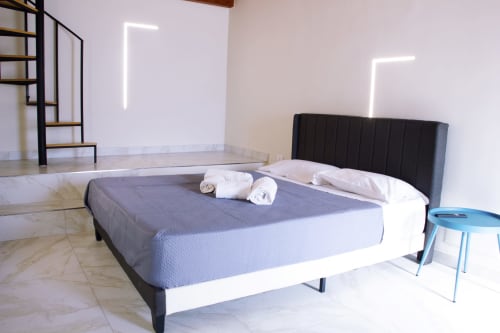 Chambre moderne au Sikania Agri Relais de Caccamo avec lit king-size, tête de lit noire, art néon et vue sur les montagnes
