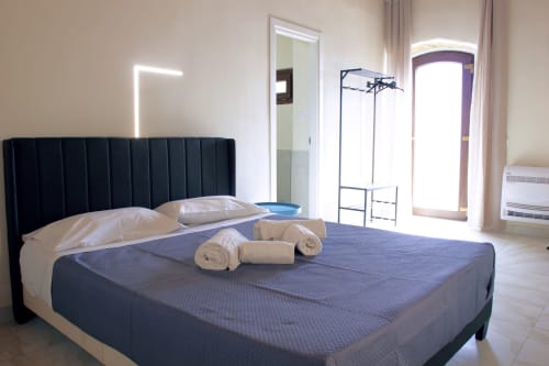 Chambre moderne au Sikania Agri Relais de Caccamo avec tête de lit noire, literie bleue et serviettes roulées