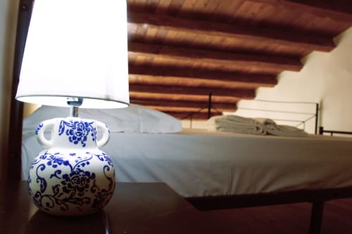 Lampe de table en porcelaine bleu et blanc dans une chambre de l'hôtel Sikania Agri Relais à Caccamo, avec poutres apparentes