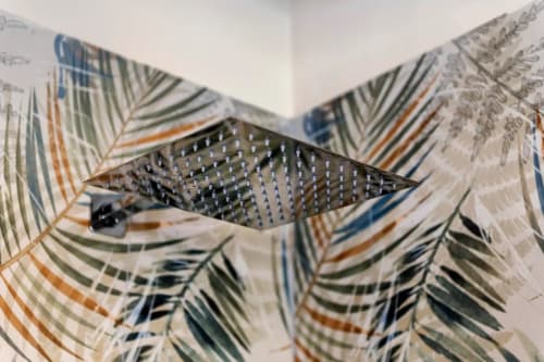 Détail du plafond avec pomme de douche de la chambre de l'hôtel Sikania Agri Relais à Caccamo, entourée de motifs de feuilles tropicales