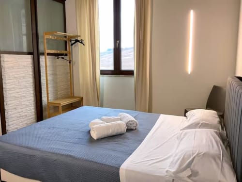 Chambre moderne à la Sikania Agri Relais à Caccamo avec vue sur les montagnes, literie bleue, oreillers blancs et portant en bois