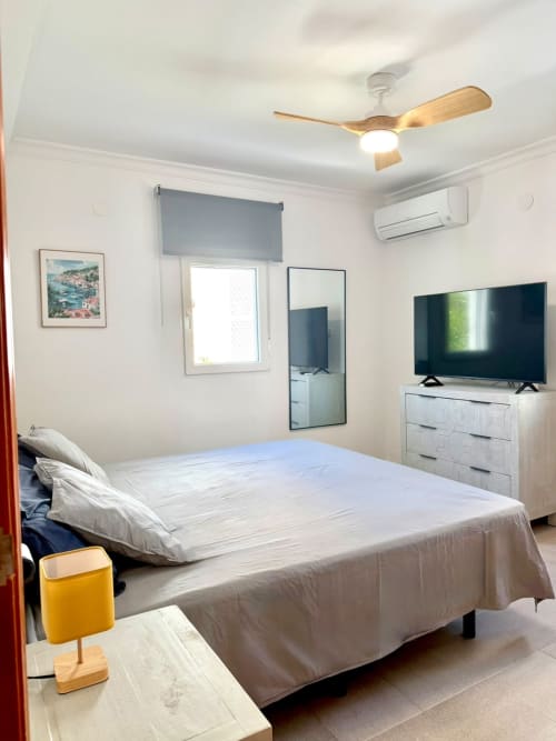 Dormitorio moderno en la casa rural Casa Mar Blau en Valencia con cama de matrimonio, TV de pantalla plana, ventilador de techo de madera y aire acondicionado