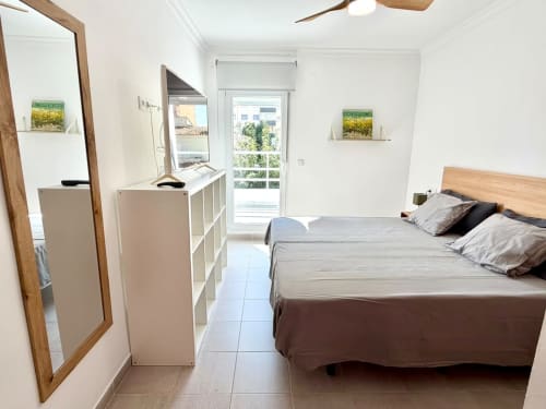 Dormitorio moderno en Casa Mar Blau, Valencia, con balcón vista al mar, cama de madera, almacenamiento blanco y diseño contemporáneo