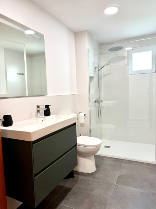Baño moderno en la casita Casa Mar Blau de Stay Gest Valencia con vanidor oscuro, lavabo blanco, inodoro y ducha caminable