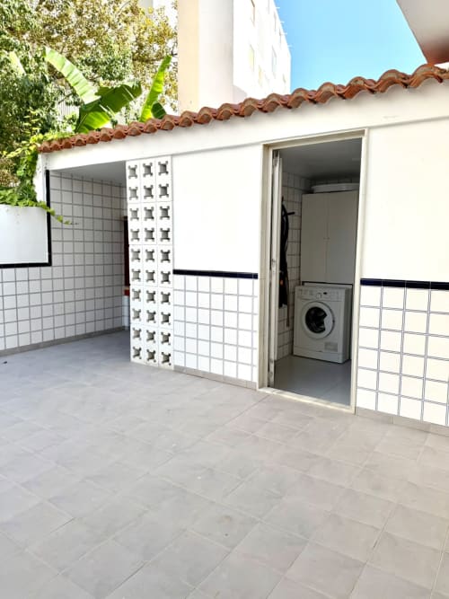 Patio de la casa rural Casa Mar Blau en Valencia con suelo de baldosas, bloques decorativos blancos y lavadora