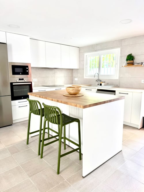 Cocina moderna en la casita Casa Mar Blau en Valencia con muebles blancos, isla de madera, taburetes verdes y acero inoxidable