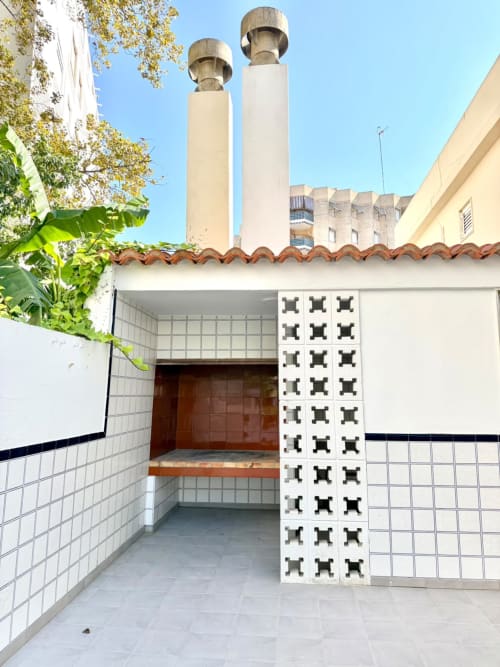 Entrada de patio exterior de la casa rural Casa Mar Blau en Valencia con paredes de azulejos, biombo decorativo y chimeneas con vista al