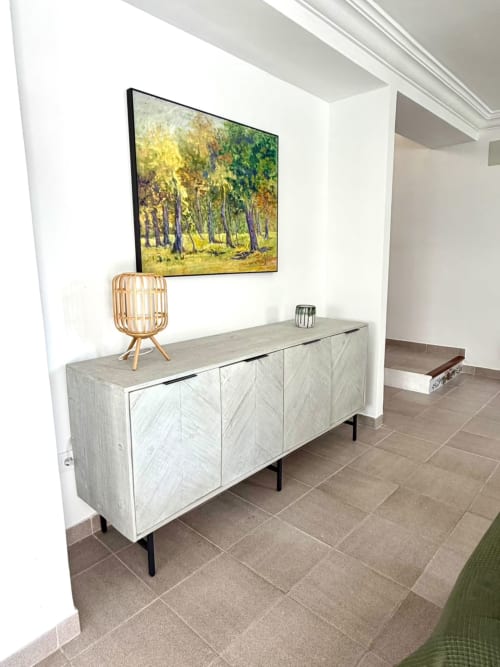 Moderna sala de estar en la casa rural Casa Mar Blau de Valencia con mueble de madera clara, televisor mostrando paisaje de bosque y textiles tejidos