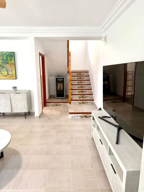 Amplia sala de estar de la Casa Mar Blau en Valencia con escalera, TV, muebles blancos y suelo de baldosas beige