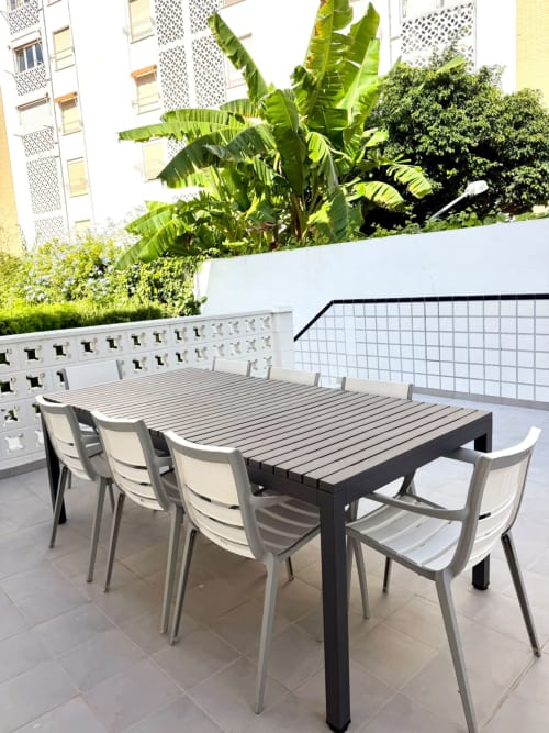 Mesa de comedor moderna con sillas blancas en un luminoso patio de Casa Mar Blau en Valencia, España
