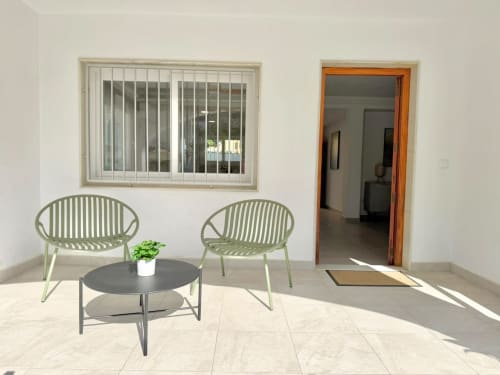 Zona de estar en la terraza exterior de Casa Mar Blau en Valencia con sillas verdes, mesa negra y vistas al mar