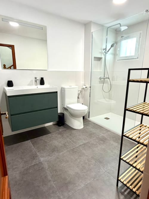 Baño moderno en la casa rural Casa Mar Blau de Stay Gest Valencia, con tocador verde, ducha a ras de suelo y herrajes elegantes