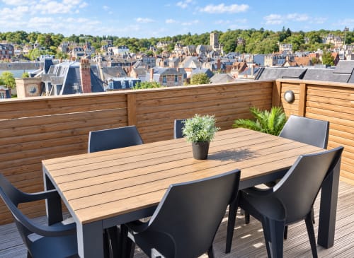 Terrasse panoramique sur le toit des Paris Normands à Boulogne avec table à manger en bois, chaises noires et vue sur la ville