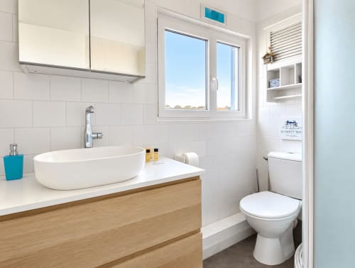 Salle de bains moderne au Gîte de Boulogne avec lavabo ovale, meuble en bois, toilettes et grande fenêtre vue mer