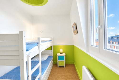 Chambre d'enfant lumineuse avec mur d'accent vert citron, lits superposés blancs, fenêtres vue mer surplombant Boulogne-sur-Mer