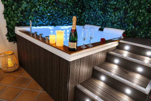 Baignoire de luxe aux Gites Saint Valery En Caux avec champagne, bougies allumées et escaliers illuminés dans l'appartement La Suite.