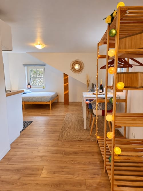 Chambre mansardée lumineuse aux Gites Saint Valery En Caux avec lit superposé en bois, lit simple, coin repas et guirlande jaune festive