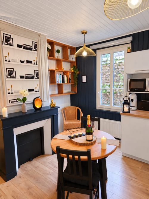 Intérieur moderne du gîte Saint Valéry-en-Caux avec table à manger, cheminée, étagères en bois et design élégant noir