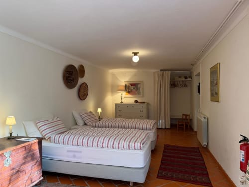 Duas camas individuais com roupa de cama às riscas vermelhas no espaçoso quarto das Mélias da Quinta da Mata de Baixo, Ferreira do Zêzere