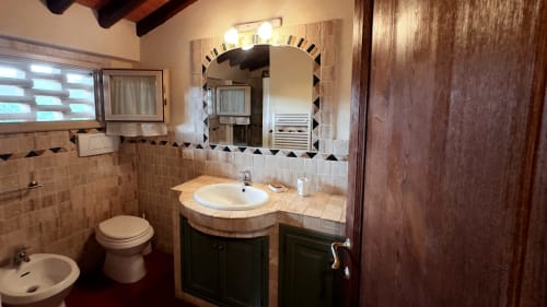 Bagno dell'appartamento Leonardo a Borgo di Erboli, Cavriglia con lavabo, specchio e pareti piastrellate